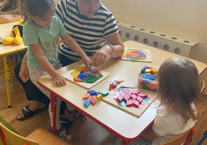 Dzieci przy stolikach układają obrazek według wzoru