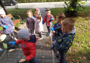 dzieci zbierają śmieci na skwerku przy bloku