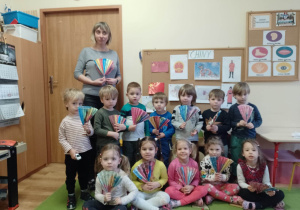 Dzieci wraz z wychowawczynią pozują do zdjęcia z własnoręcznie zrobionymi wachlarzami