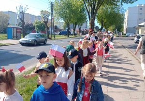 Dzieci z flagami w rękach spacerują ulicami osiedla w rytm poloneza