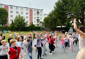 Dzieci bacznie obserwują panią instruktorkę zumby i starają się wykonywać te same ruchy w rytm muzyki