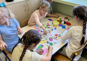 Dziewczynki wykonują magnesy dla mamy i taty z wykorzystaniem różnorodnych naklejek