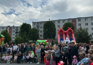 Rodzice i dzieci gromadzą się w ogrodzie przedszkolnym na Festynie Rodzinnym