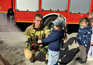 Dzieci leją wodę z węża gaśniczego