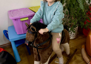 Dziewczynka buja się na koniku na biegunach