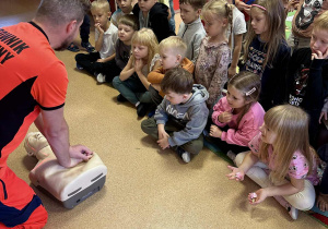 Ratownik pokazuje jak powinno wyglądać prawidłowe uciskanie