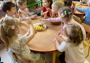Dzieci jedzą owoce przy stolikach