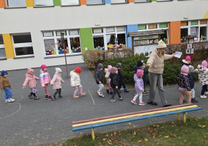 Dzieci na placu zabawa mierzą odległość, stawiając stopy jedna za drugą.