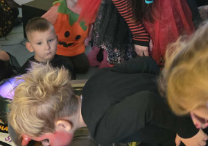 Chłopiec "łowi" jabłko umieszczone w misce z wodą zębami