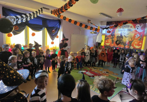 Dzieci w kole tańczą z miotłami