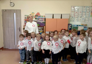 Dzieci pozują do zdjęcia wraz z panią nauczycielką- wszyscy mają na sobie kotyliony