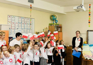 Dzieci z grupy Pszczółek śpiewają piosenkę "Jaki piękny kraj" trzymając w rękach flagę Polski