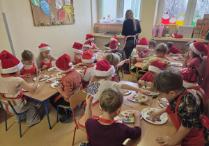 Dzieci przy stolikach dekorują świąteczne pierniki