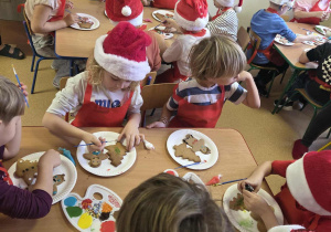 Dzieci ozdabiają lukrem piernikową choinkę i ludzika