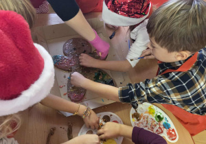 Dzieci wspólnie dekorują wielkiego piernika