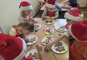 Dzieci w skupieniu dekorują wypieki świateczne