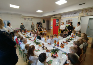 Dzieci siedzą przy stolikach i częstują się przygotowanym jedzeniem
