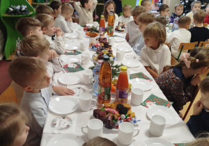 Dzieci siedzą przy pięknie nakrytych stolikach