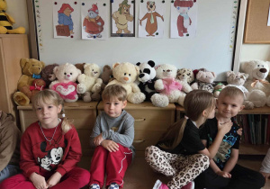 Dzieci siedzą przy tablicy ze swoimi misiami