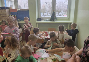 Dzieci przy stolikach wykonują pracę plastyczno-techniczną " Święty Mikołaj"