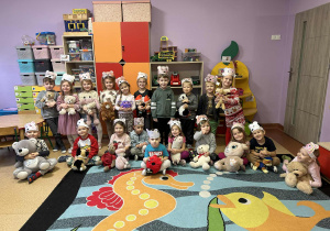 Dzieci pozują do zdjęcia z opaskami "misia" na głowie i swoimi pluszakami