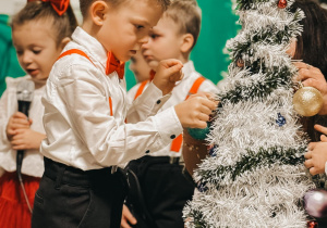 chłopiec wiesza bombkę na choince.