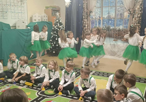 Dziewczynki tańczą w parach/trójkach a chłopcy grają na dzwonkach