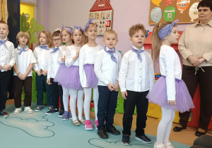 Dzieci ustawione w półkolu występują przed swoimi dziadkami