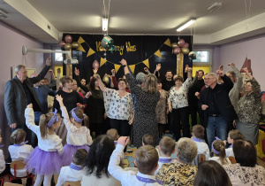 Dziadkowie tańczą w rytm muzyki z pacynką sterowaną przez nauczycielkę