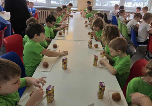 Dzieci po zawodach sportowych jedzą słodki poczęstunek w szkolnej stołówce