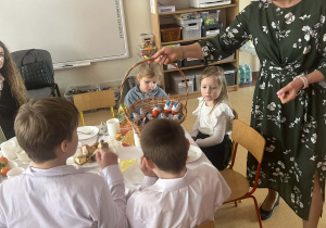 Pani dyrektor rozdaje dzieciom czekoladowe jajka