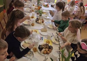 Dzieci jedzą wielkanocne śniadanie - żur z białą kiełbasą i jajkiem