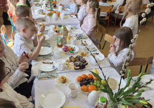 Dzieci przy stole jedzą słodkie, świąteczne wypieki