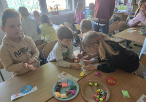 Dzieci w grupach wylepiają plasteliną postać Plastusia
