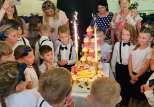 Dzieci ustawiają się wokół tortu i słodkiego poczęstunku