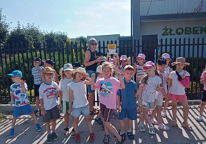 Pszczólki wraz z wychowawczynią przyczepiają do furtki przedszkola ostatnie zadanie dla Misiów