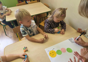 Dzieci przyklejają kolorowe kółka tworząc gąsienicę