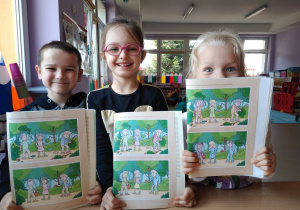 dzieci prezentują wzorowo wykonane zadanie w książce dotyczące prawidłowego dbania o przyrodę
