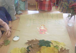 Dzieci przyklejają liście do sukni "Pani Jesieni"