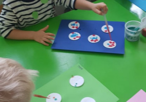 Dzieci ozdabiają farbami waciki kosmetyczne w kształcie koła