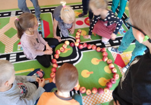 Dzieci z jabłek tworzą "kontur wielkiego jabłka" na dywanie