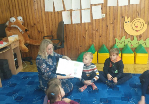 Dzieci uważnie słuchają czytanej przez panią Olę książki