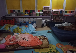 Dzieci słodko śpią na materacach w sali.