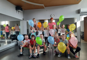 Dzieci, nauczycielka i instruktorka fitness pozują do zdjęcia z balonami