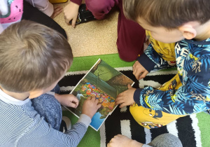 Dzieci układają puzzle przedstawiające ilustrację bajki