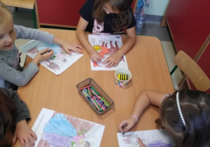 Dzieci starannie kolorują ilustracje z bajek