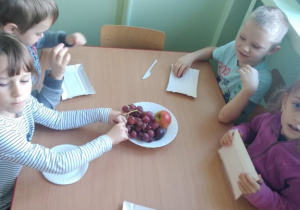 Dzieci przy stolikach szykują owoce do szaszłyków