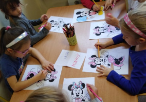 Dzieci przy stolikach kolorują postać Myszki Miki i Myszki Minnie