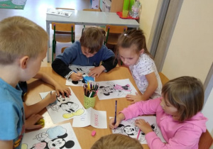 Dzieci według wzoru podpisują swoją pracę przedstawiającą Myszkę Miki lub Myszkę Minnie
