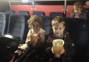 Dzieci jedzą popcorn w kinie